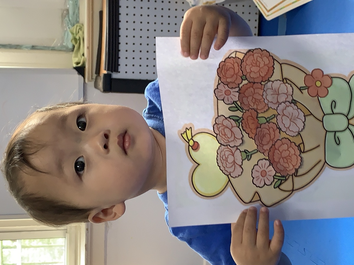 小男孩展示亲手制作的康乃馨花束感恩贴画作品
