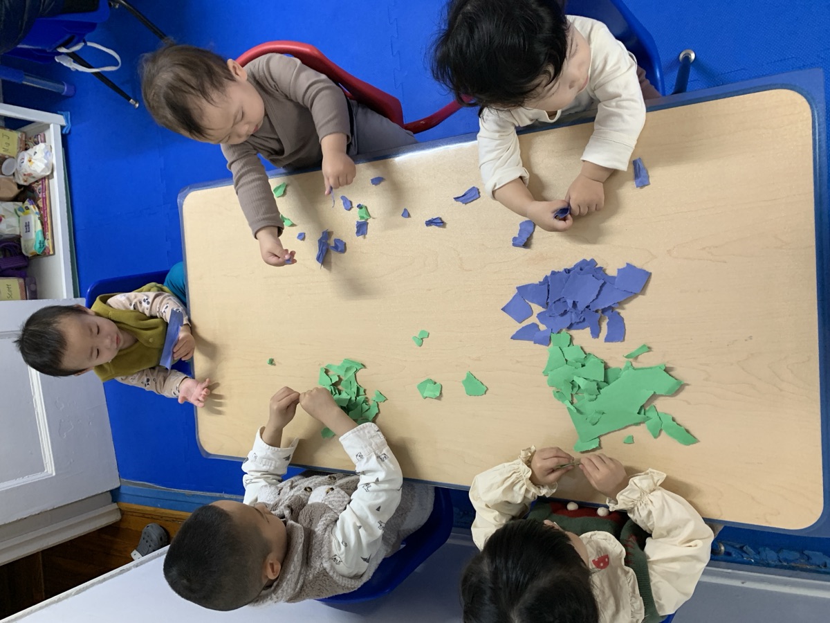 孩子们围桌专注地玩彩泥与撕贴游戏