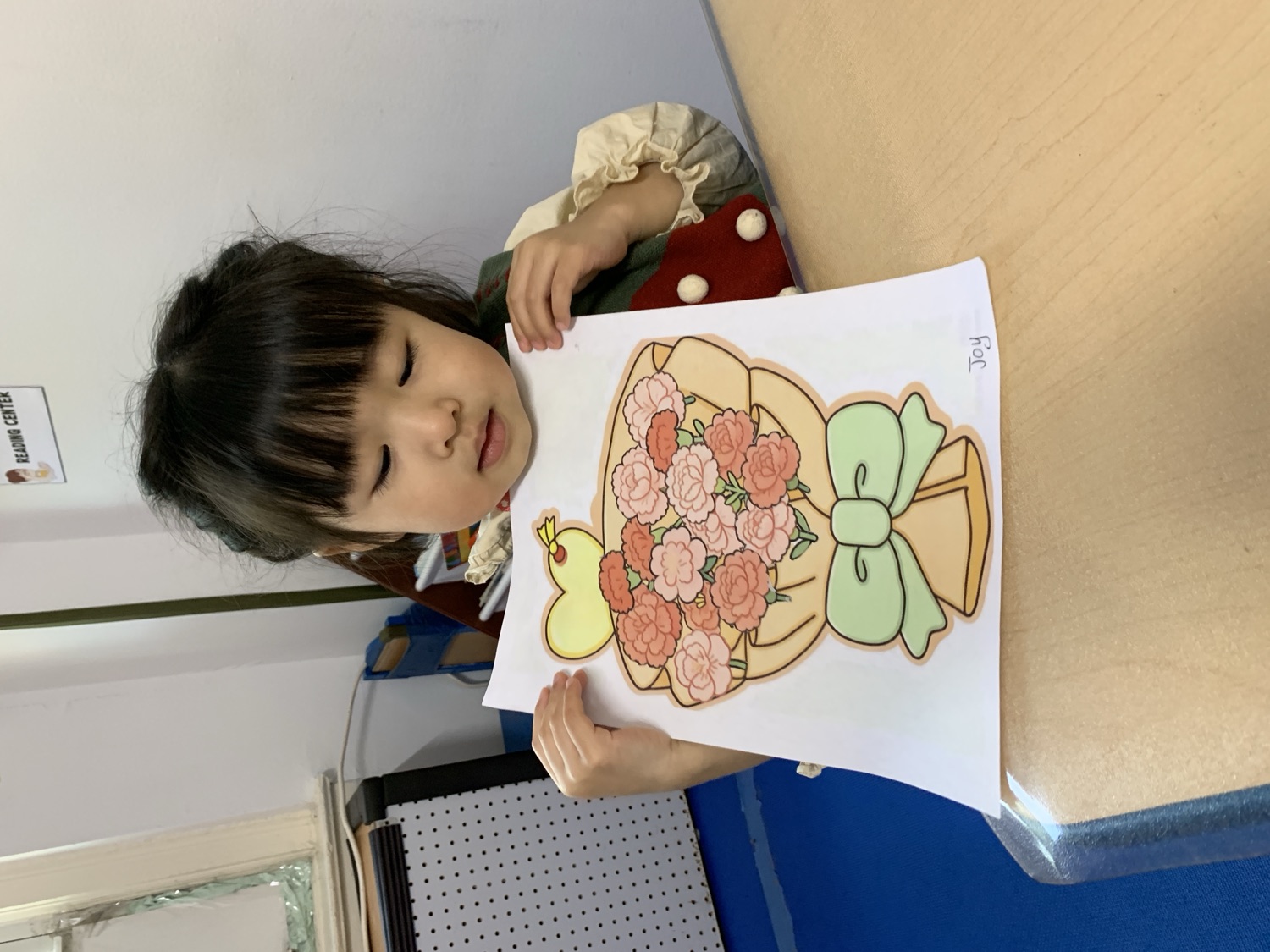 小女孩展示她涂色完成的鲜花花束作品
