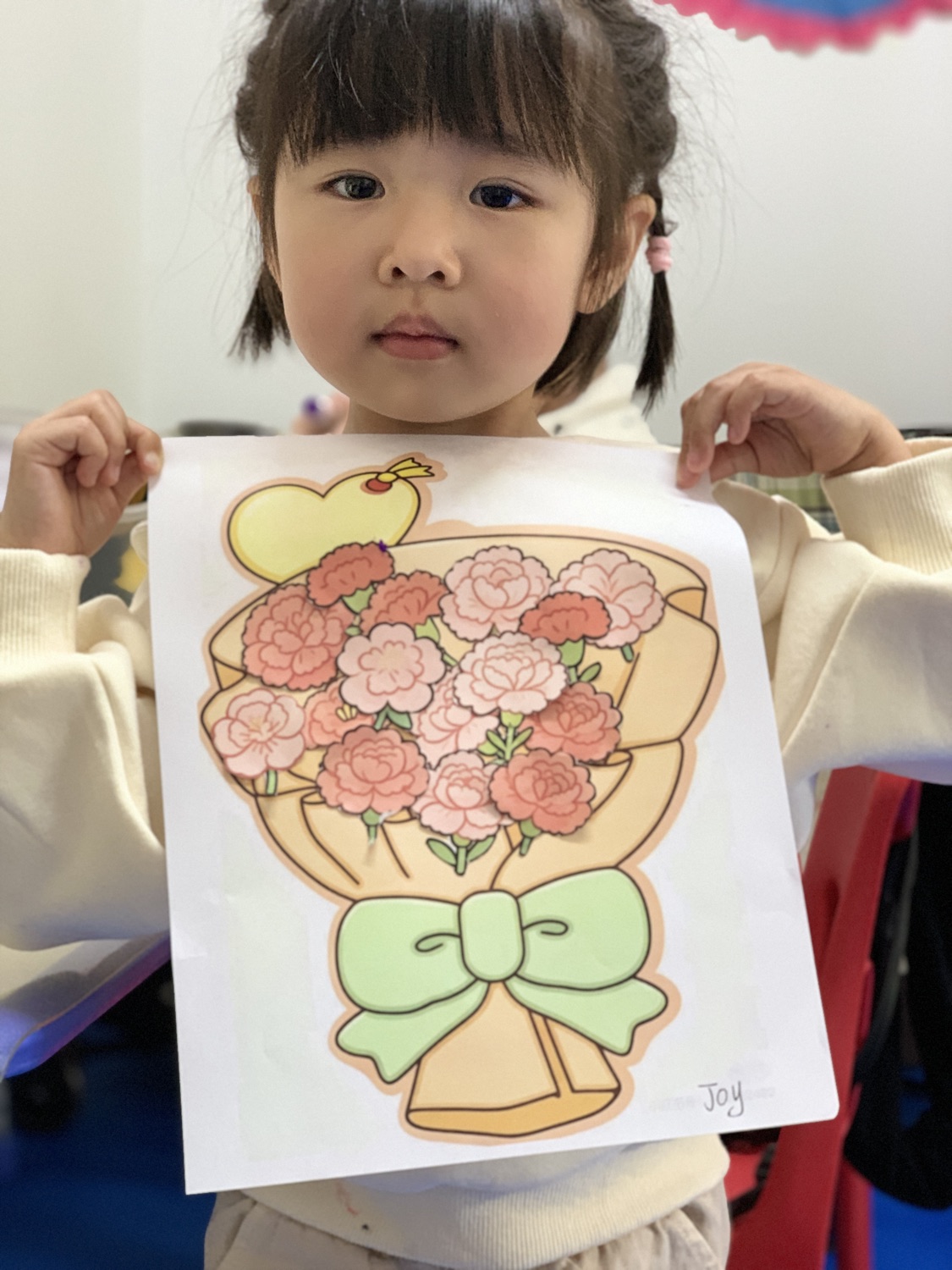 小女孩展示她涂色完成的康乃馨花束作品