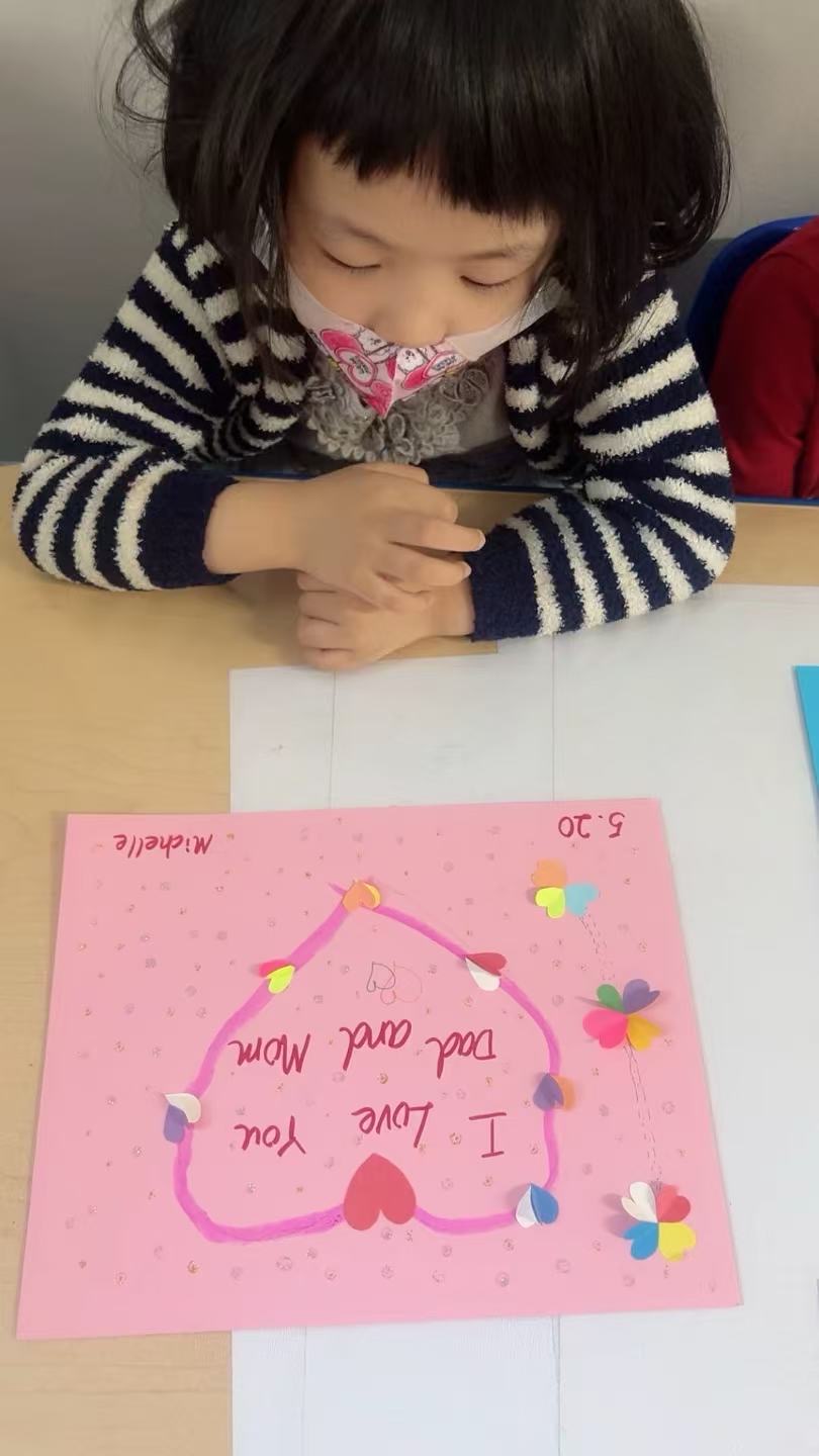 小女孩专注制作I Love You Dad and Mom爱心感恩贺卡