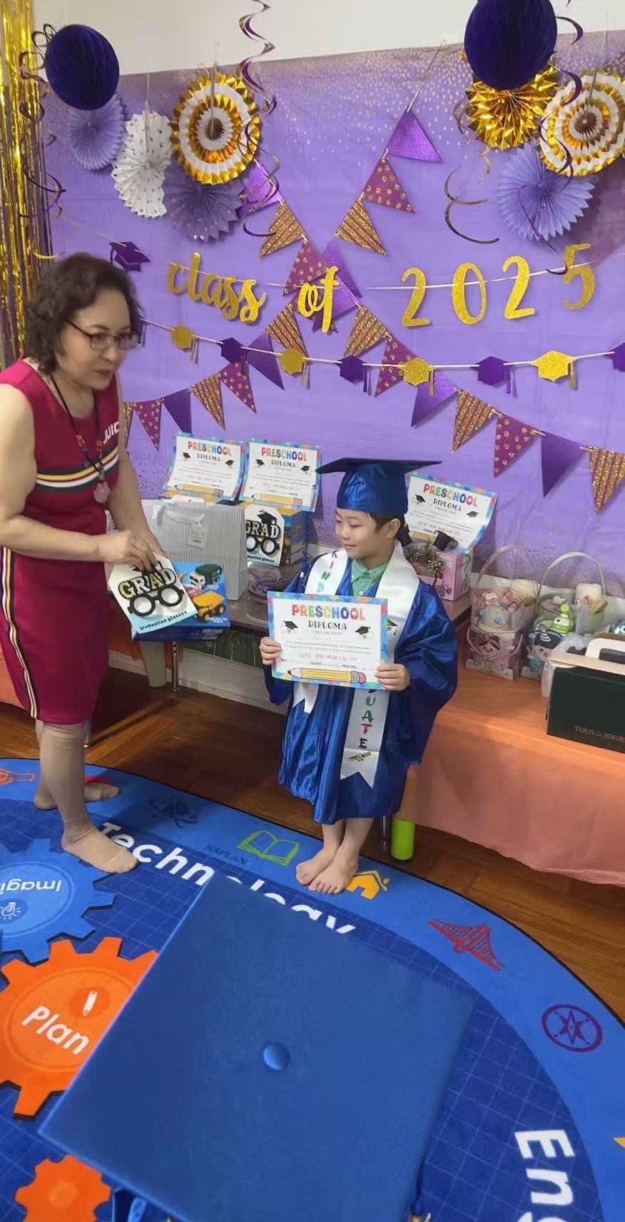 老师为身穿蓝色学士服的毕业小朋友颁发幼儿园毕业证书