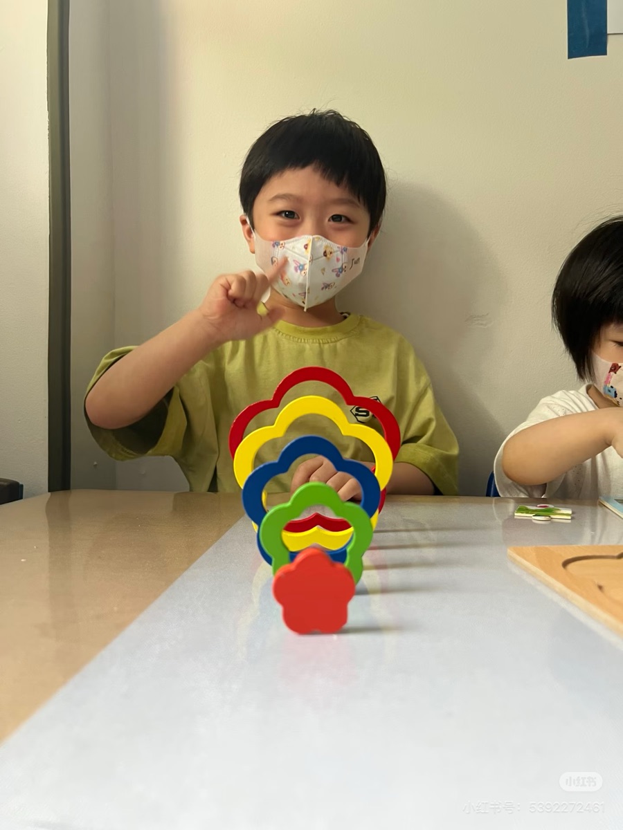 小男孩在桌边玩彩色花朵形状叠叠乐益智玩具